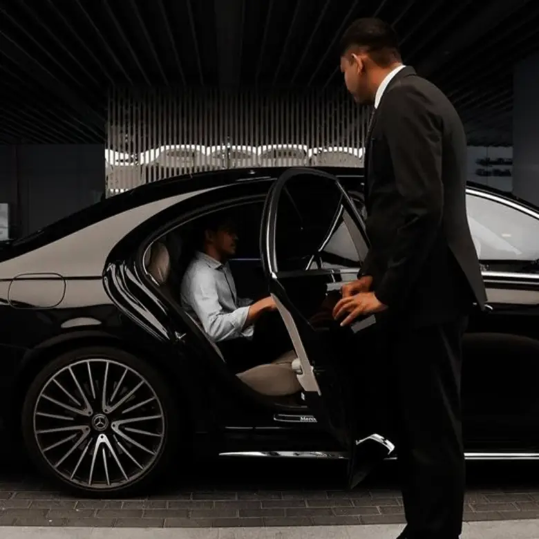 Private chauffeur opening luxury sedan door for executive client in Thailand